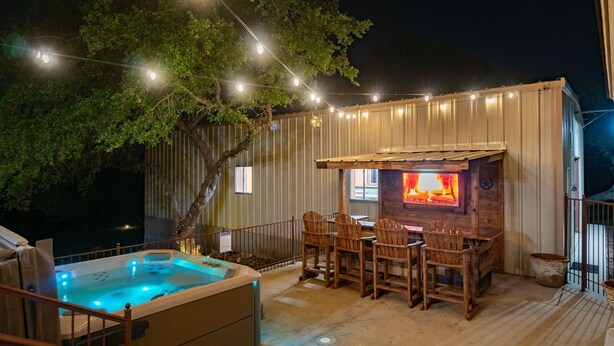 An outdoor patio with a hot tub, wooden chairs, a fire pit, and string lights. - Hot Tub/Shuffleboard/Pool Table near Guadalupe Riv. & Lake (New Braunfels)