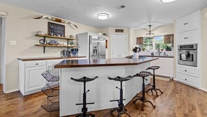 A modern kitchen with a large island, stainless steel appliances, and a farmhouse sink. - Hot Tub/Shuffleboard/Pool Table near Guadalupe Riv. & Lake (New Braunfels)