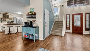 A spacious living area with a kitchen, a staircase, and a door with decorative glass panels. - Hot Tub/Shuffleboard/Pool Table near Guadalupe Riv. & Lake (New Braunfels)