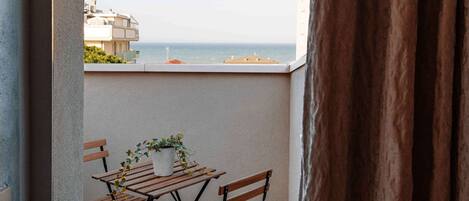 A balcony with a view of the sea, featuring a table and chairs.