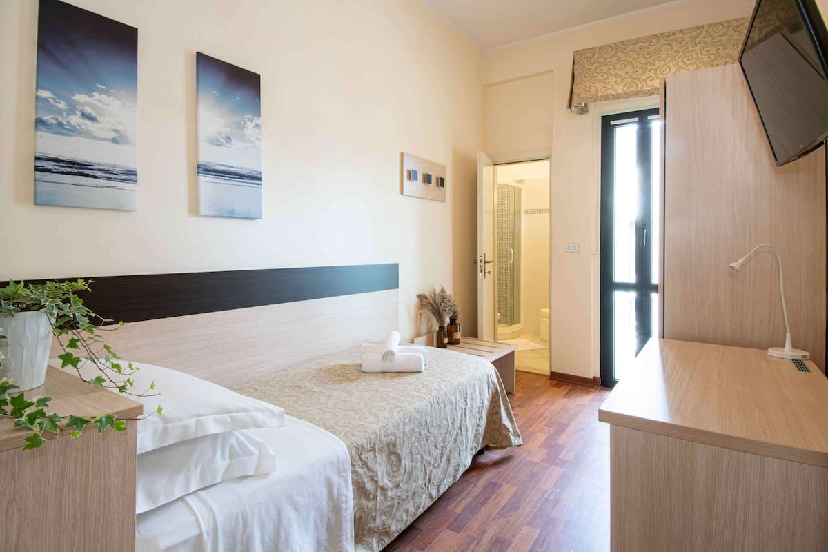 Une chambre d’hôtel avec deux lits, un bureau, une télévision et un espace douche.