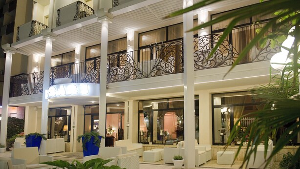 Un hotel de diseño moderno, con una amplia zona de estar al aire libre con mobiliario blanco y plantas en macetas.
