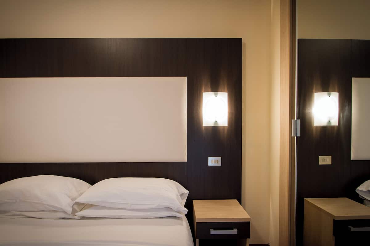 Une chambre d’hôtel avec un grand lit, des tables de chevet et un miroir.