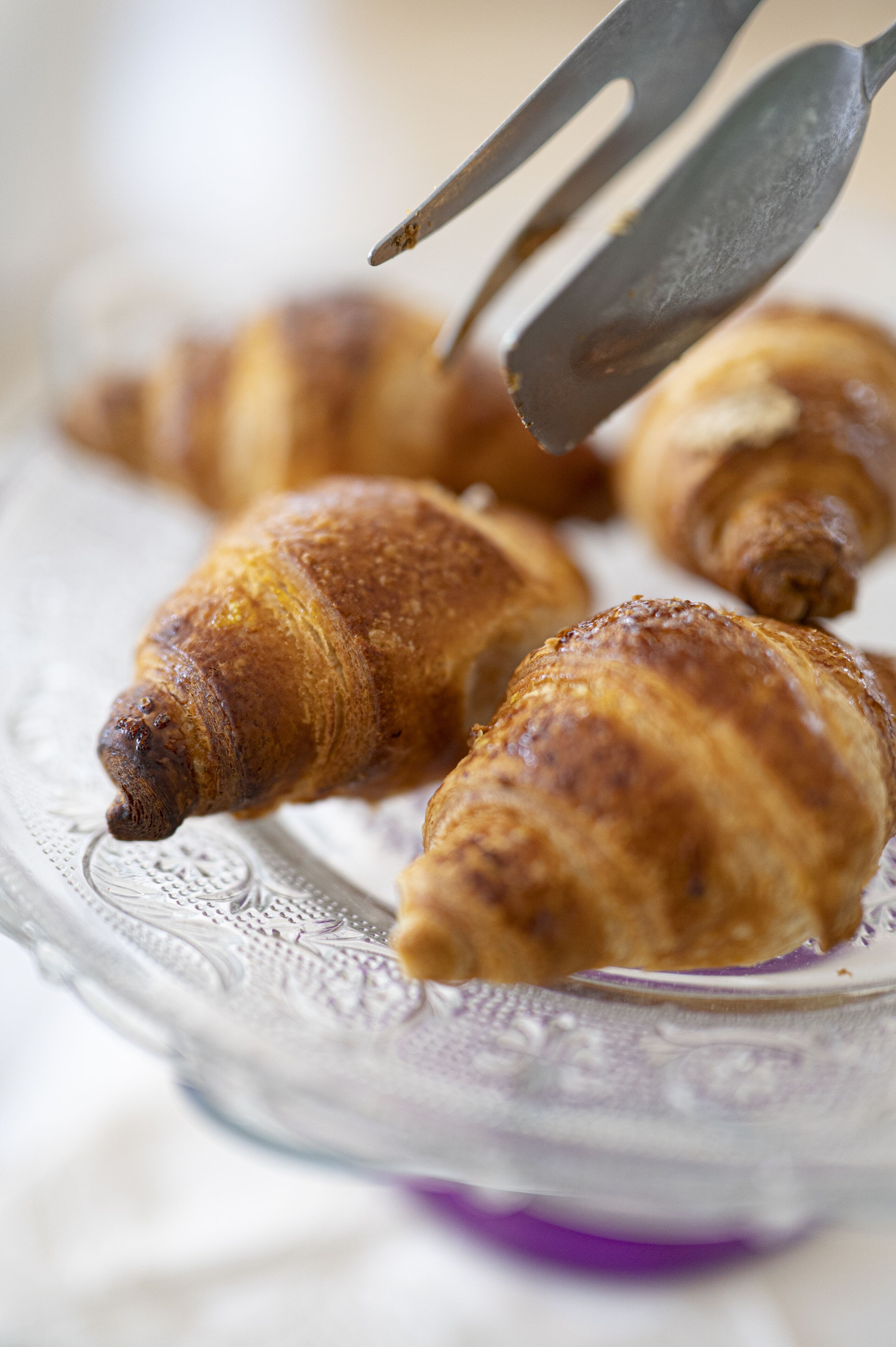 A close-up of croissants on a glass plate with a fork.