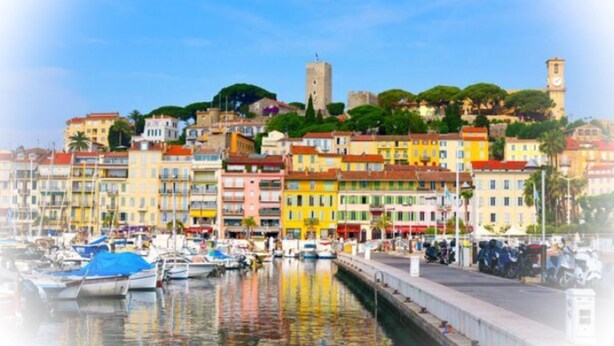 Une ville côtière aux bâtiments aux couleurs vives, dotée d’un port de plaisance et d’une tour imposante.
