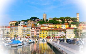 Un pueblo costero con edificios coloridos, un puerto deportivo y una torre destacada.