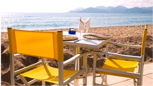 Une table avec des chaises, une bouteille et un verre, installée sur la plage.