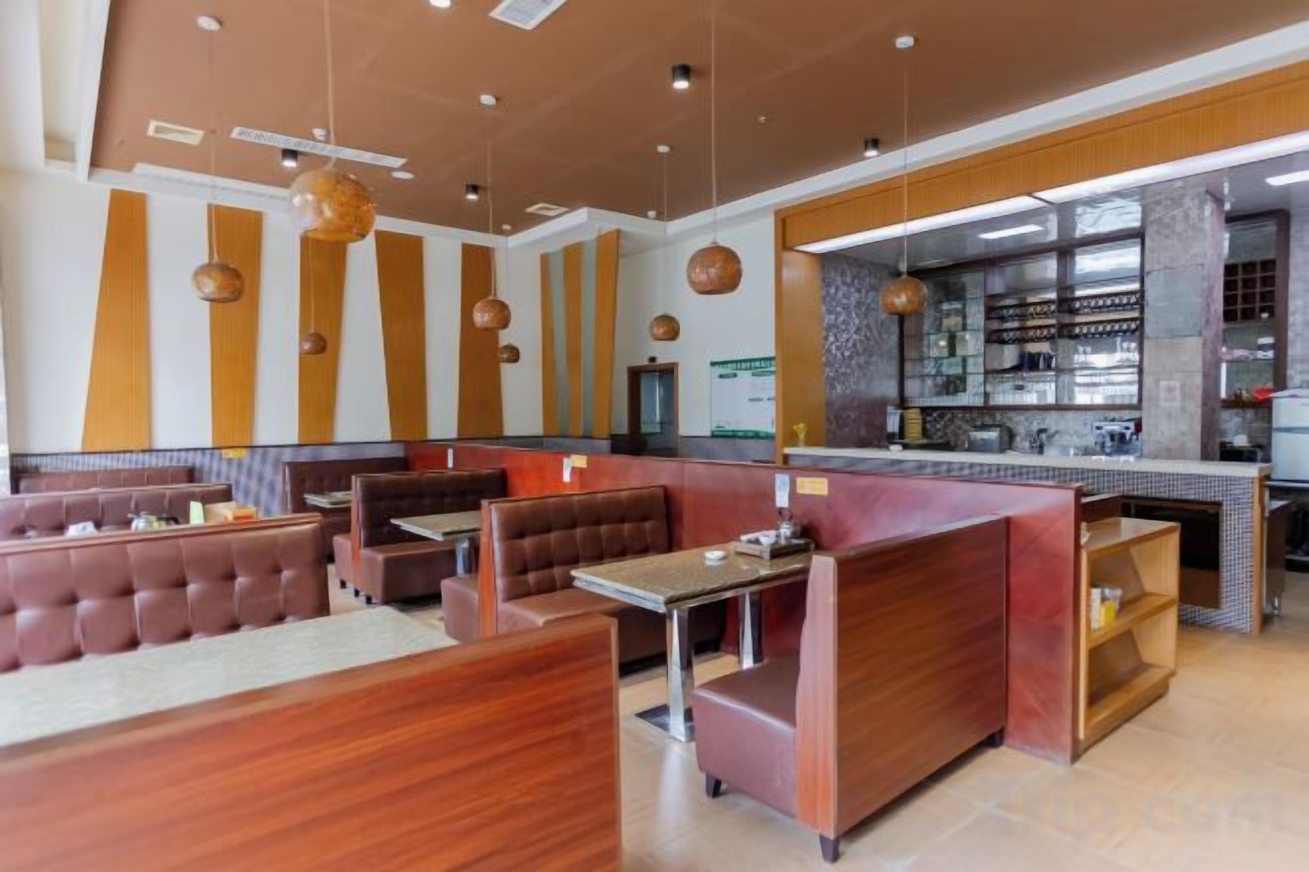 A restaurant with booths and tables, a kitchen area, and a counter.
