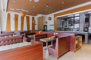 Un restaurante con mesas, cabinas y una barra, además de una zona de cocina.