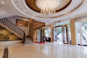 Un vestíbulo amplio con una imponente escalera, un candelabro y una recepción.