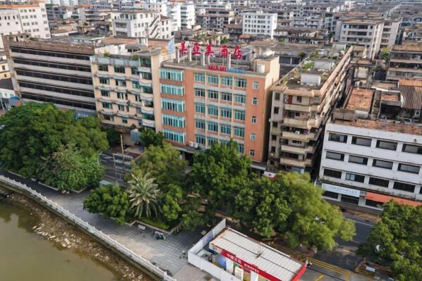 A multi-story building with a prominent red sign, surrounded by other buildings and trees. - Meiyamei Hostel (Kaiping)