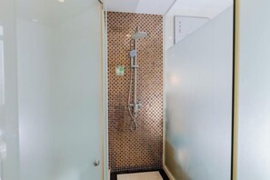 A shower with a checkered tile wall, a handheld showerhead, and a wall-mounted faucet. - Meiyamei Hostel (Kaiping)