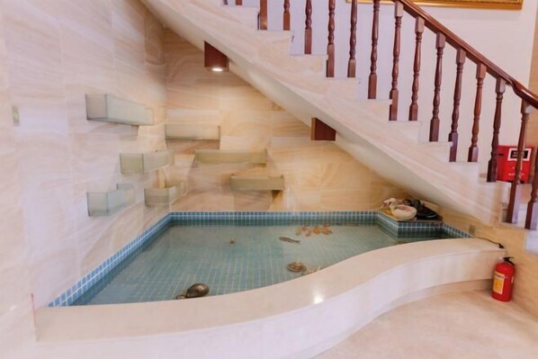 A spa area with a small pool, wooden staircase, and a fire extinguisher. - Meiyamei Hostel (Kaiping)