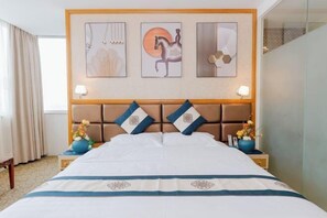 A hotel room with a large bed, two nightstands with lamps, and three framed artworks on the wall. - Meiyamei Hostel (Kaiping)