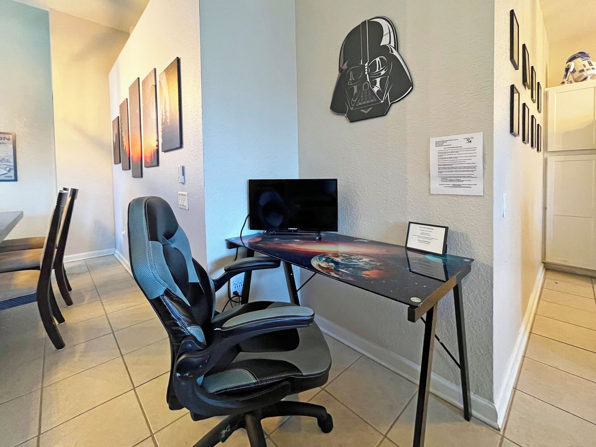 Un espacio de oficina moderno con un escritorio, una silla alta y un monitor de ordenador fijado a la pared.