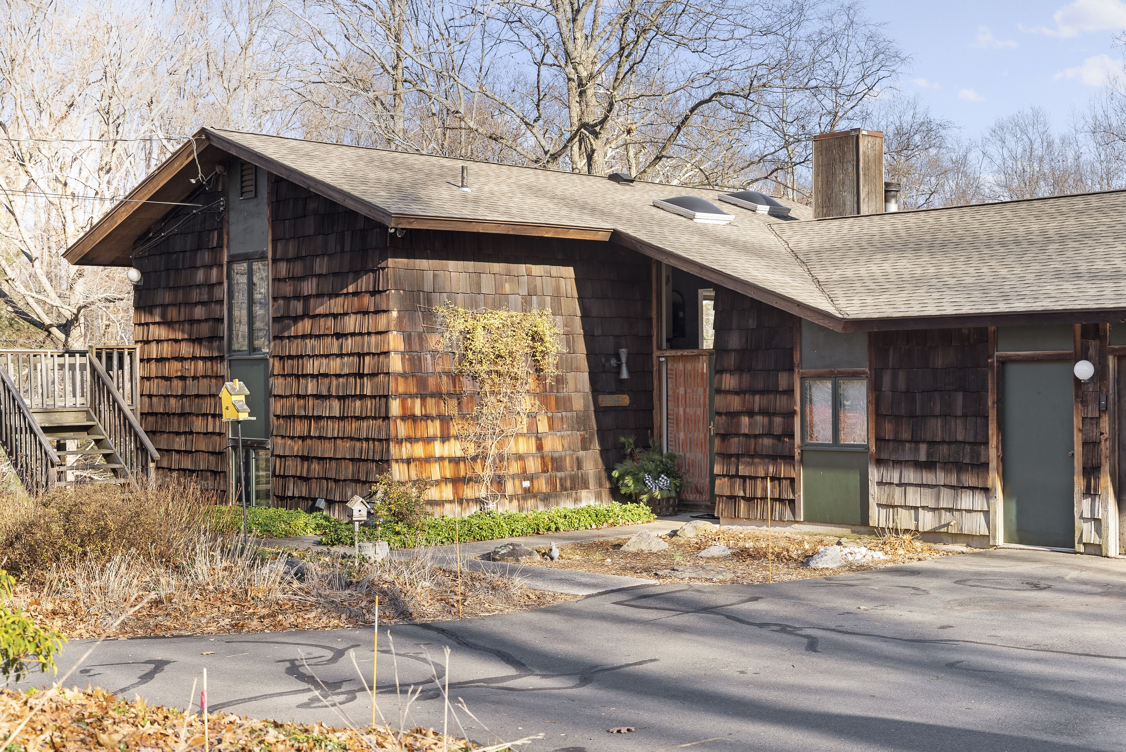 A wooden cabin with a sloped roof, a chimney, and a small porch area.