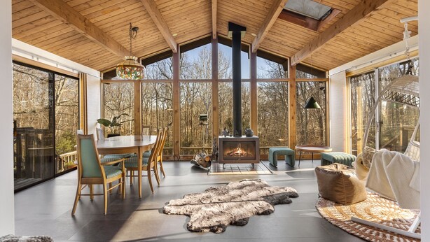 A spacious room with a large wooden ceiling, a fireplace, and a view of the outdoors. - The Connecticut Chalet - On 5 Acres! (Southington)