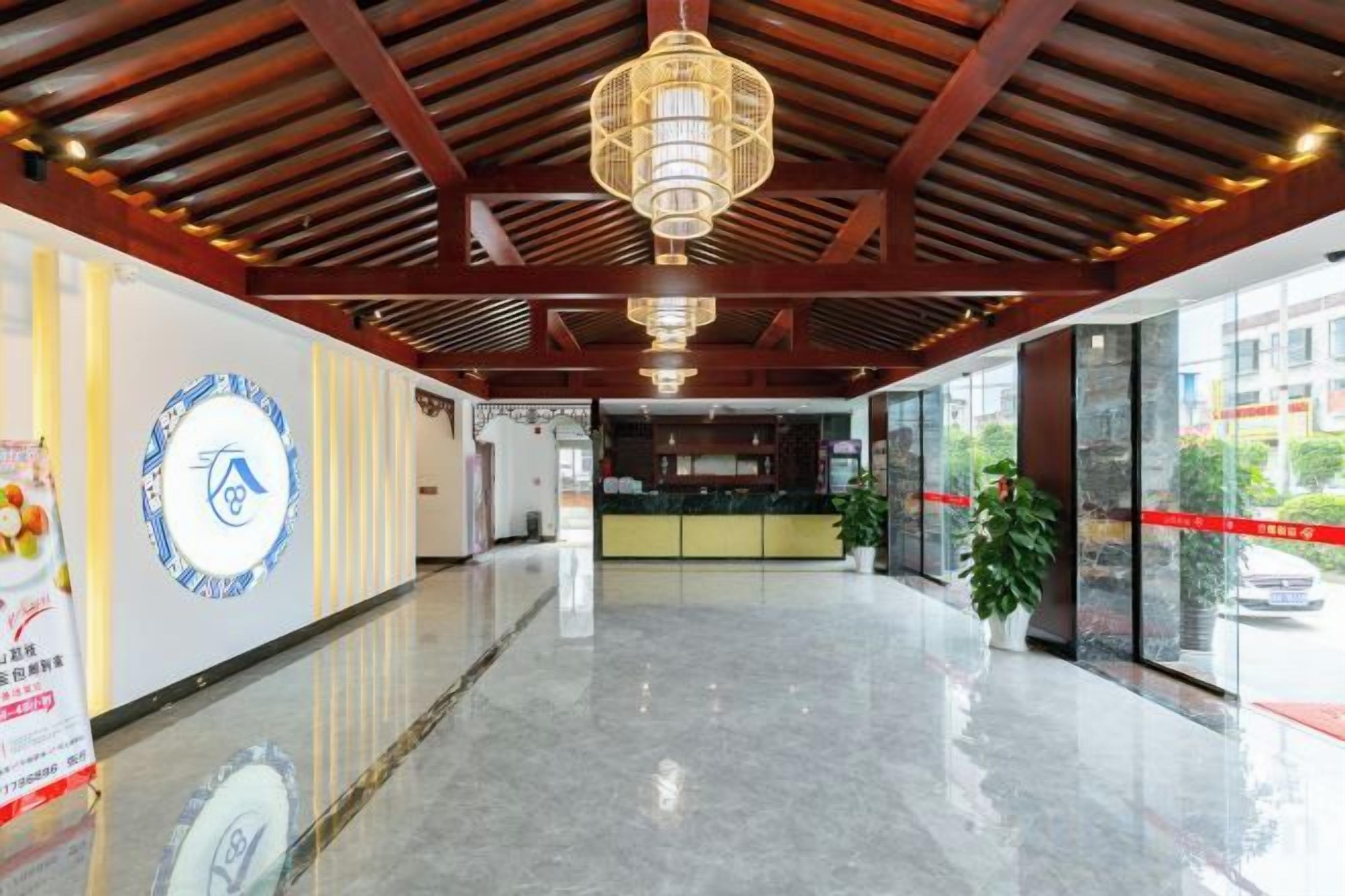 A hotel lobby with a reception desk, a chandelier, and a large window.