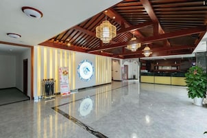 A spacious lobby with a polished marble floor, a reception desk, and a large wall clock.