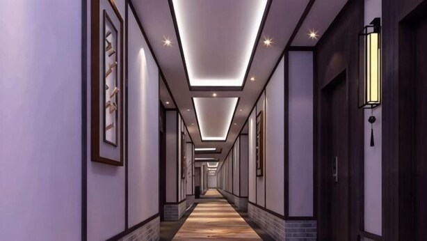 A long, narrow hotel corridor with framed artwork on the walls, recessed lighting, and a patterned carpet. - Lijin Hotel (Lingshan)
