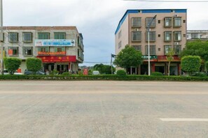 A street view with buildings, a road, and greenery. - Lijin Hotel (Lingshan)
