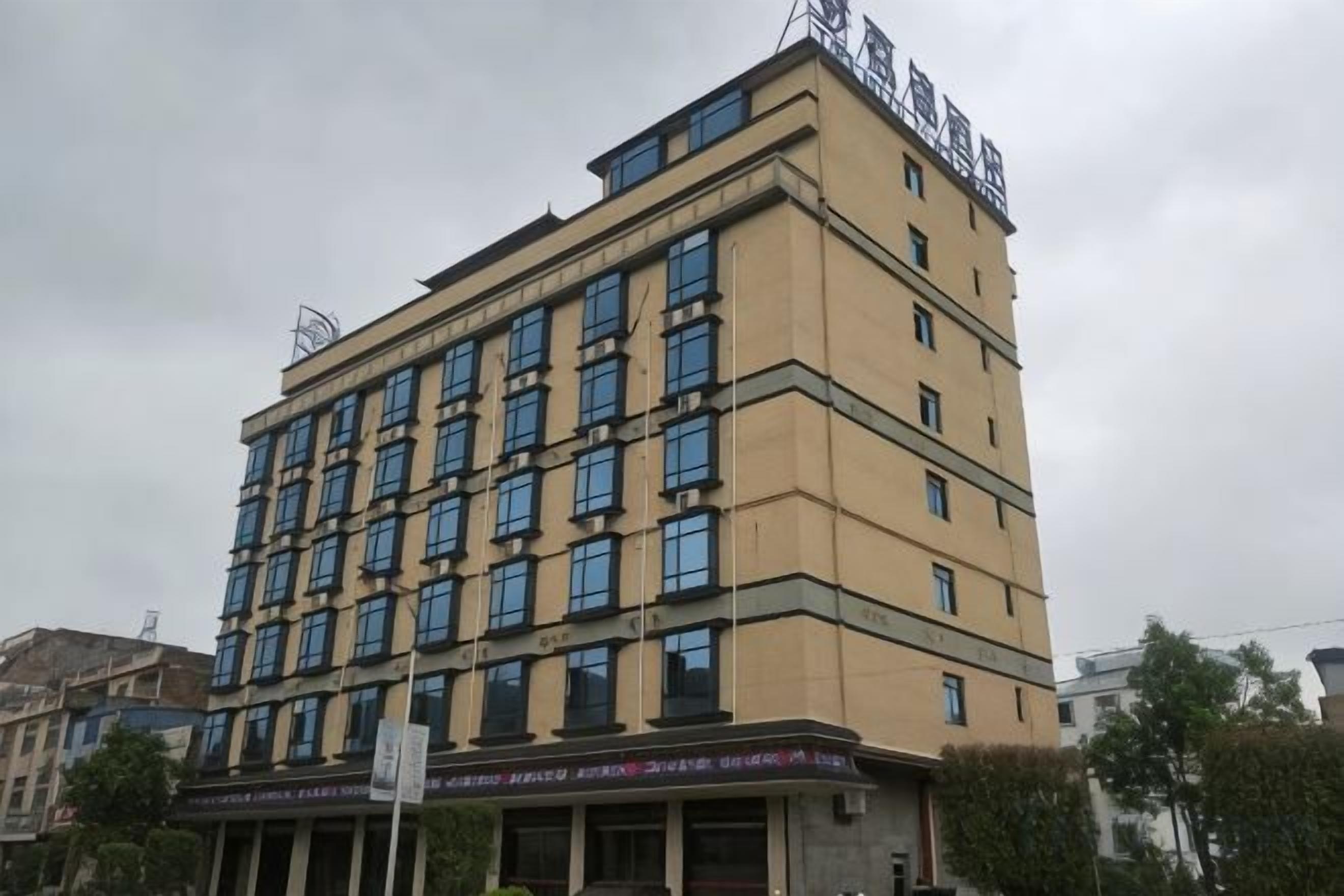 Un hôtel à plusieurs étages, doté d’une façade plate, de nombreuses fenêtres et d’une enseigne au sommet.