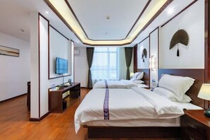 Habitación de hotel con dos camas, televisión, escritorio y un ventanal grande.