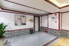 A lobby with a tiled floor, a reception desk, and a fire extinguisher. - Lijin Hotel (Lingshan)