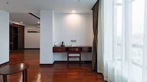 A modern hotel room with a wooden floor, a desk with a chair, a large window with sheer curtains, and a visible air conditioning unit. - Lijin Hotel (Lingshan)