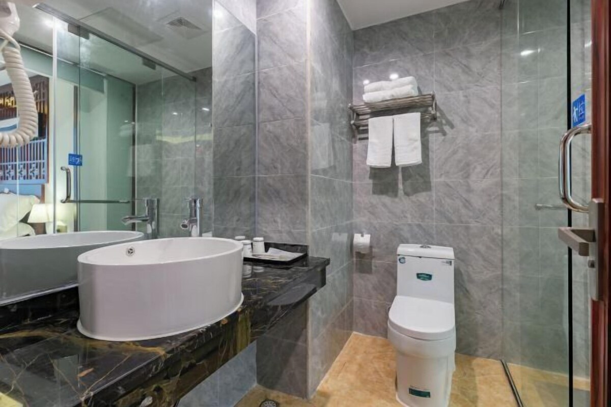 Un baño moderno con un lavamanos ovalado grande, un inodoro y una cabina de ducha de vidrio.