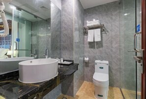 Un baño moderno con un lavamanos ovalado grande, un inodoro y una cabina de ducha de vidrio.