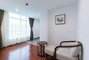 Una habitación con piso de madera, una mesa redonda, una silla acolchada y un cuadro en la pared.