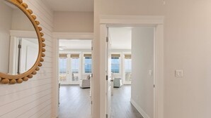 Um corredor com um espelho grande e uma porta que dá para um quarto com varanda.