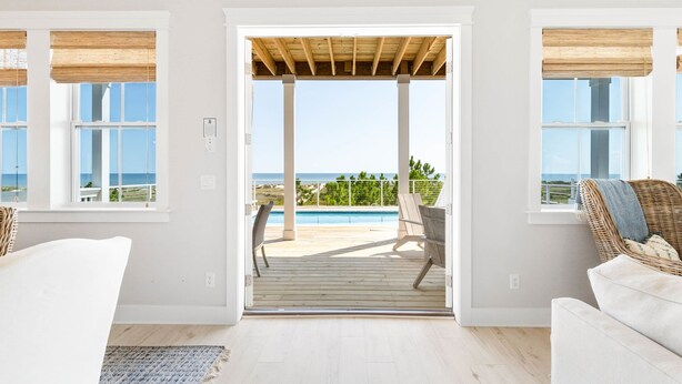A room with a view of a pool and the ocean, a wooden deck, and a white interior. - Monterey Oceanfront Beach House (Port St. Joe)