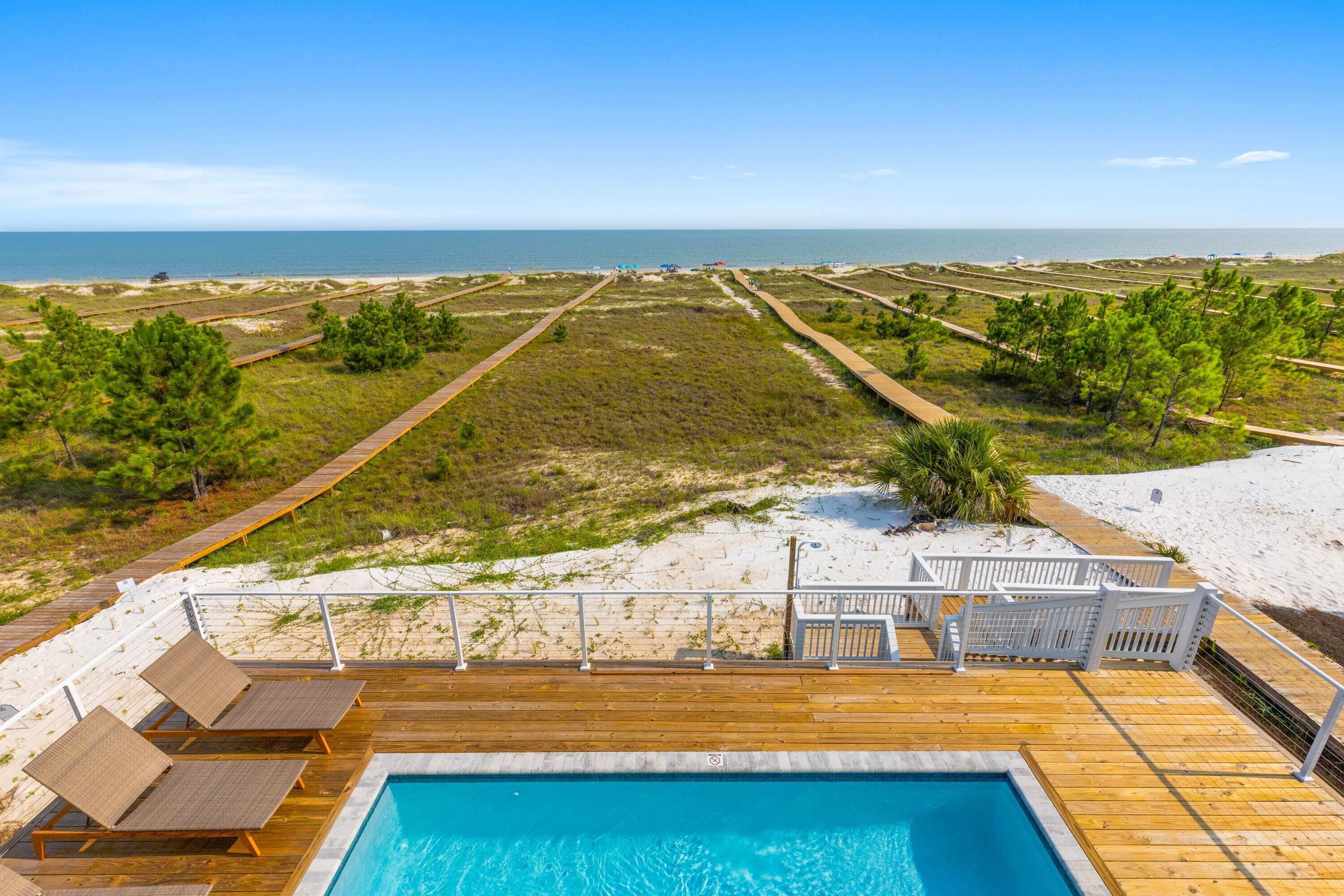 A pool area with a view of the beach and ocean.