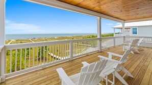A wooden deck with white railings and Adirondack chairs overlooking a beach. - Killarney Oceanfront Beach House Summer (Port St. Joe)