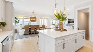 A spacious kitchen with a large island, white cabinetry, and hanging pendant lights. - Killarney Oceanfront Beach House Summer (Port St. Joe)