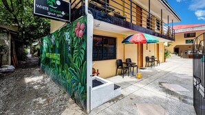 Un hotel con un letrero que dice "WHITE SHAMROCK Beach Hotel", zona de estar al aire libre y una escalera que lleva a un nivel superior.