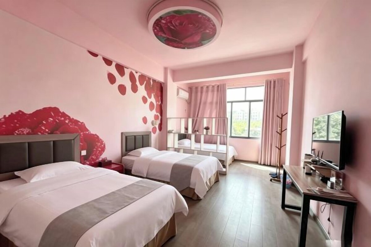 Habitación de hotel con dos camas, televisión, escritorio y un amplio ventanal.