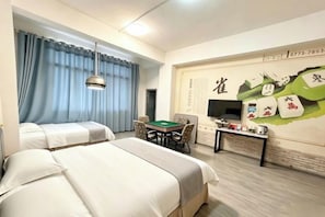 A hotel room with two beds, a desk with a computer, a television, and a wall with a decorative mural.