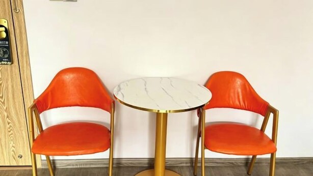 A room with two orange chairs and a round table with a gold base. - Fenglin Art Hotel (Pingle)