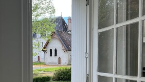 A room with a large window, a wooden door, and a view of a traditional building with a sloped roof.