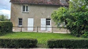 A two-story house with a tiled roof, white doors, and a chimney.