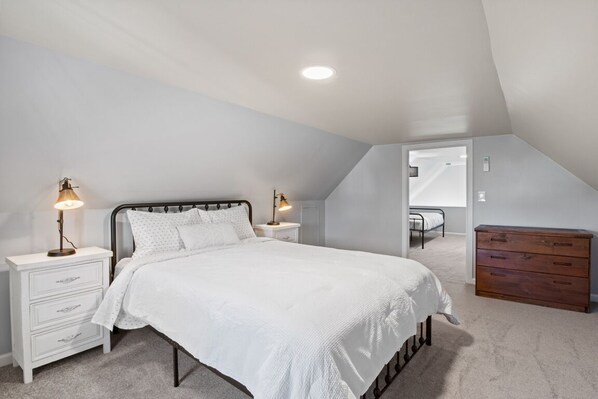 Un dormitorio con cama, mesitas de noche, cómoda y vestidor.