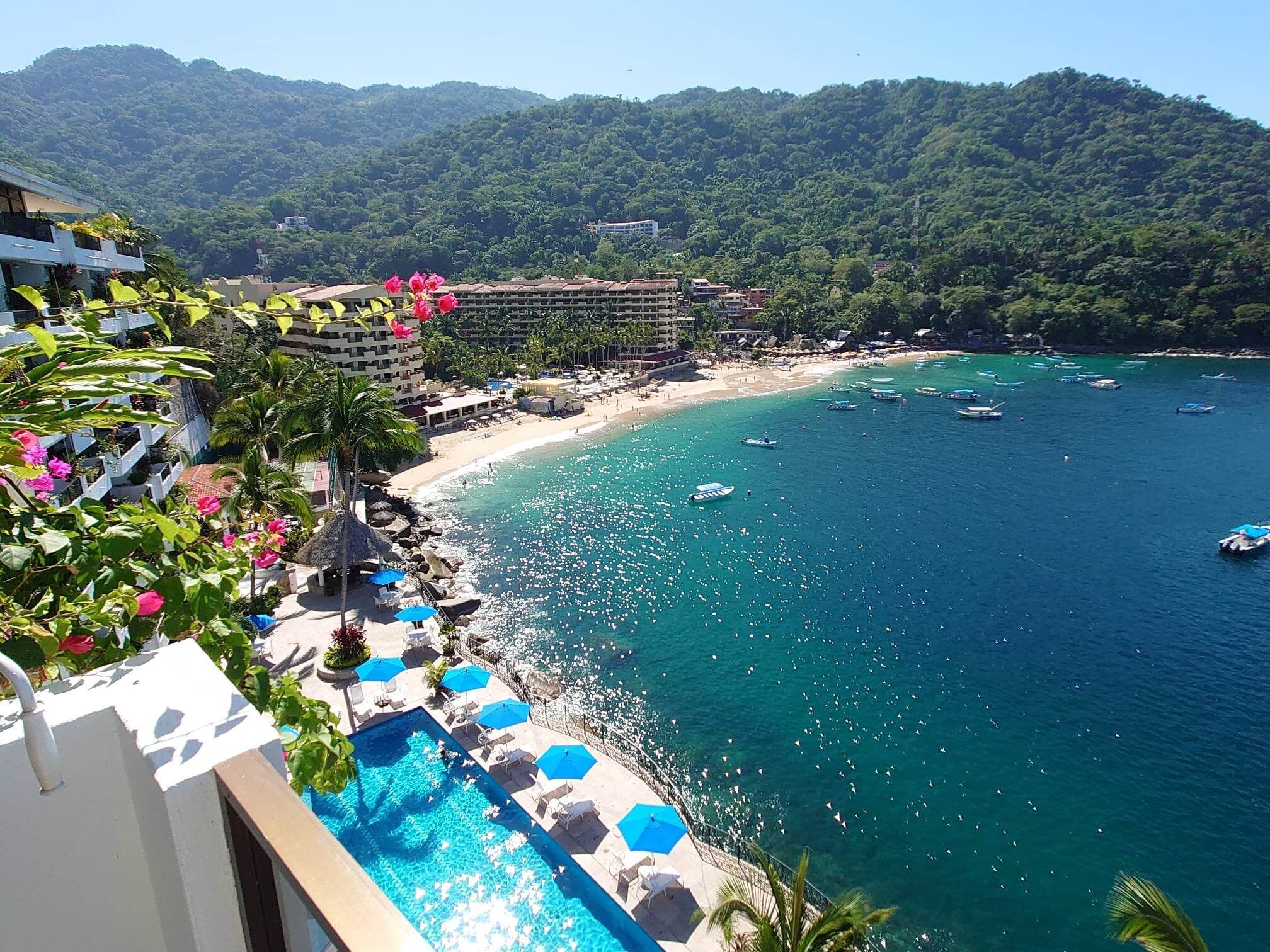A resort with a pool, beach, and boats.