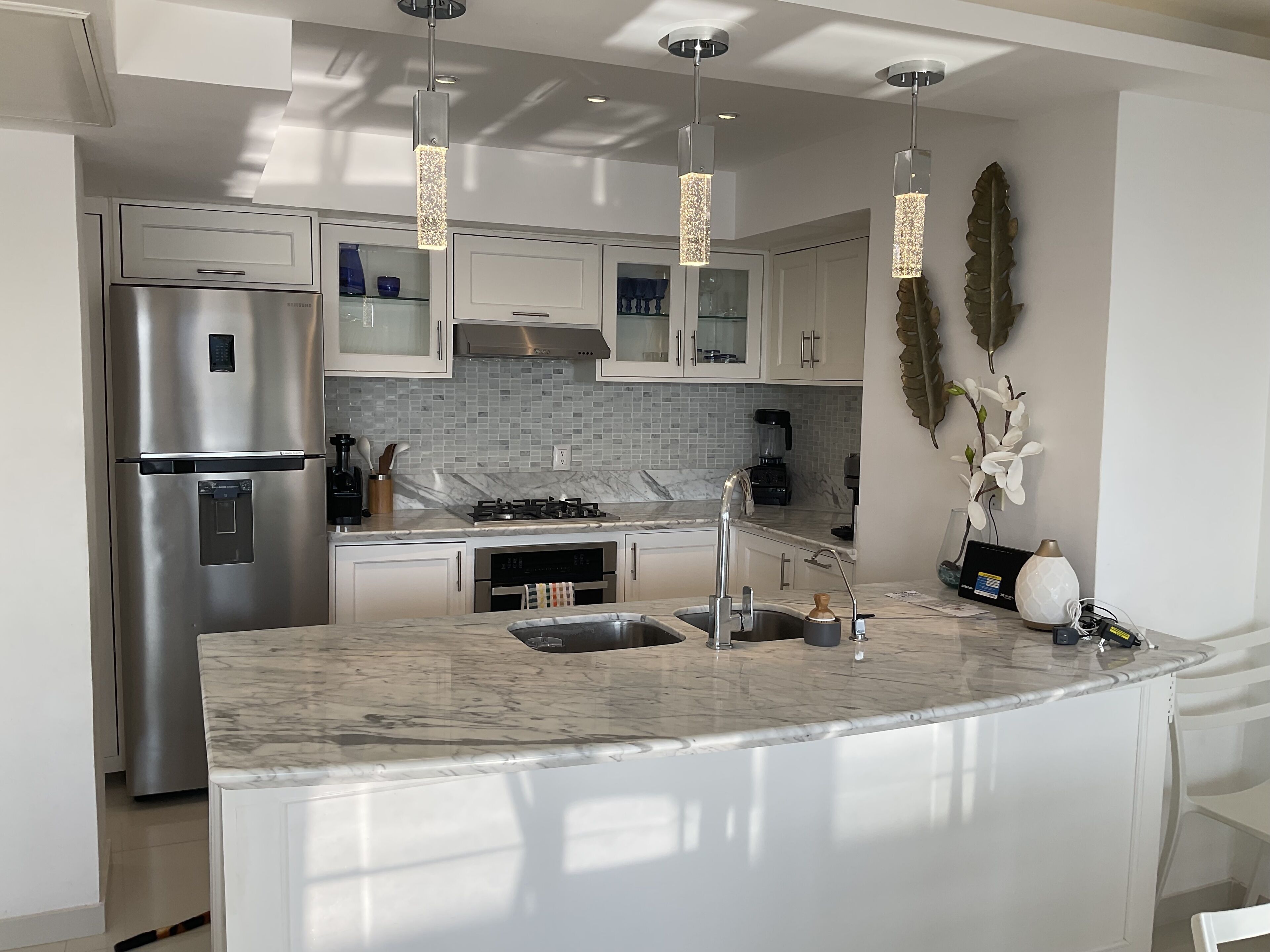 A modern kitchen with a stainless steel refrigerator, a gas stove, and a marble countertop.