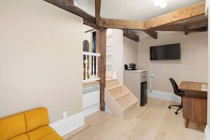 Un interior moderno con una escalera, un escritorio de madera y un sofá amarillo.