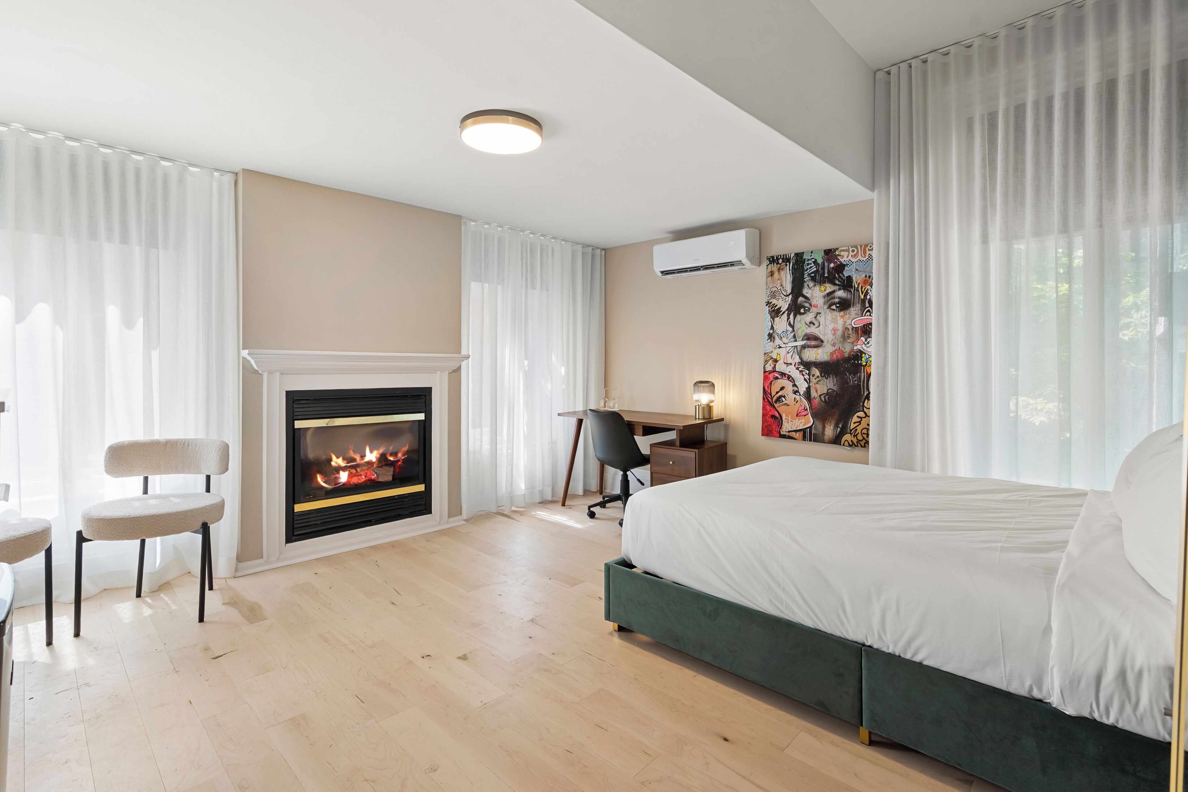 Une chambre d’hôtel moderne équipée d’une cheminée, d’un lit, d’un bureau et d’une chaise.