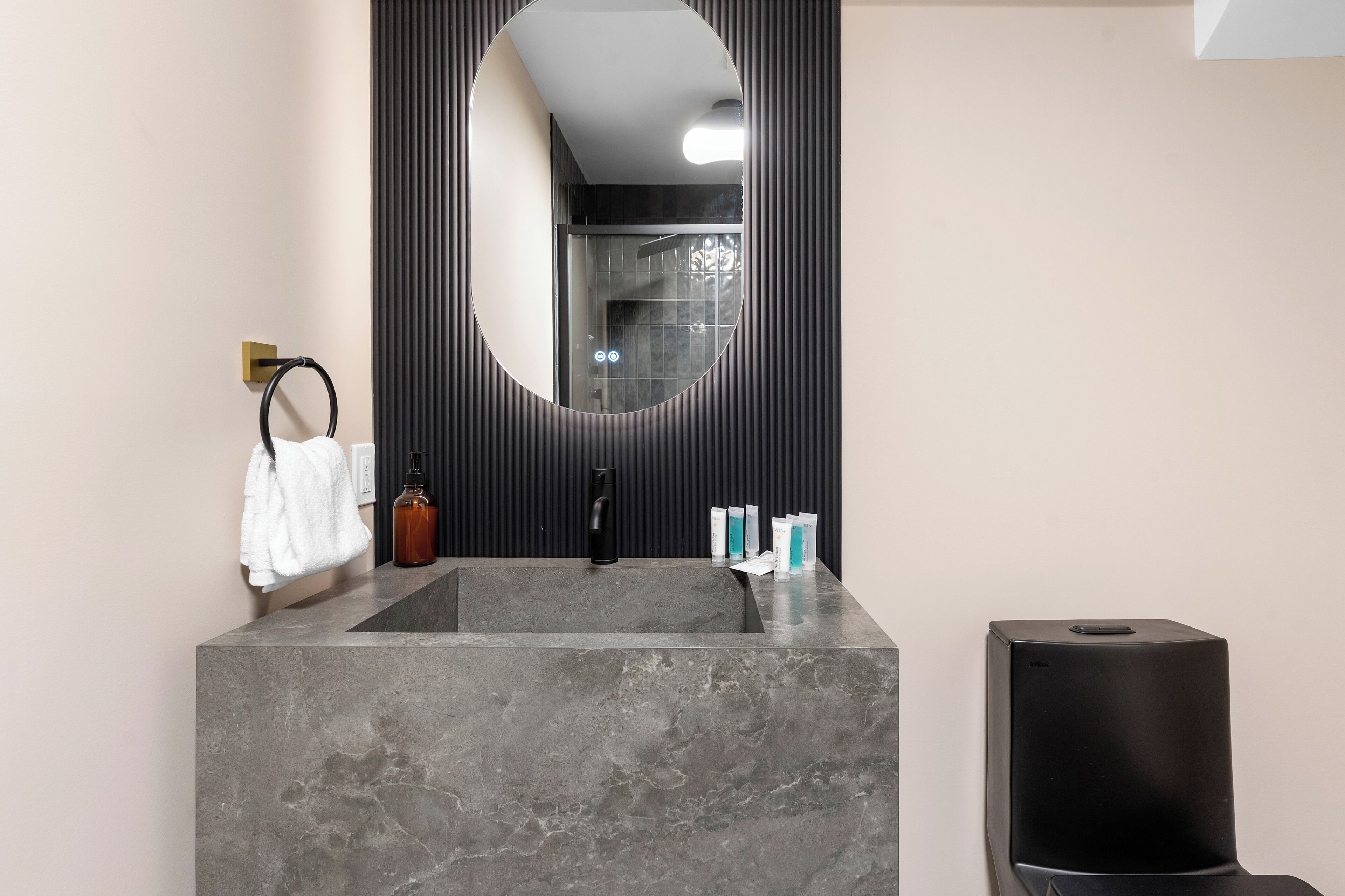 A bathroom with a marble sink, a black faucet, a towel rack, and a mirror.
