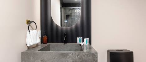 A bathroom with a marble sink, a black faucet, a towel rack, and a mirror.